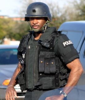 A police officer in uniform standing next to a car.