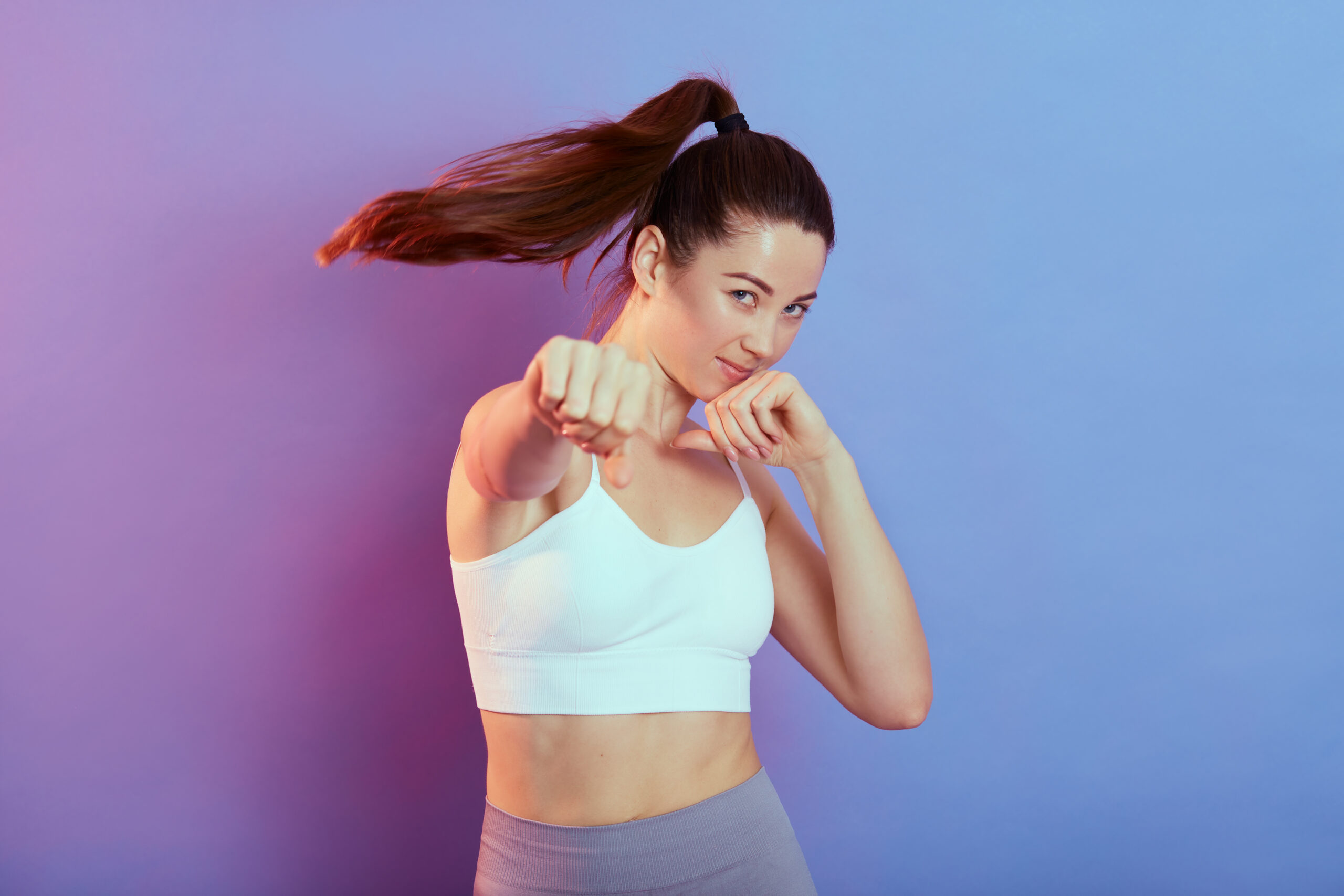 A woman in white top and gray shorts holding her fist.